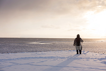 One of the last remaining Inughuit subsistence hunters, Naimanngitsoq Kristiansen, stands on watch with his rifle for marine mammals at the ice edge, Greenland, Denmark, Polar Regions