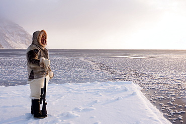 One of the last remaining Inughuit subsistence hunters, Naimanngitsoq Kristiansen, stands on watch with his rifle for marine mammals at the ice edge, Greenland, Denmark, Polar Regions