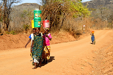 Women on dirt road carrying water on head, Tanzania, East Africa, Africa