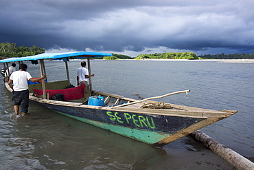 Dark clouds and tourist boat on the Manu river, Manu National Park, UNESCO World Heritage Site, Peru, South America