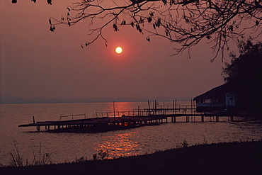 Sun setting over jetty and waters of Lake Ypacarai in Paraguay, South America