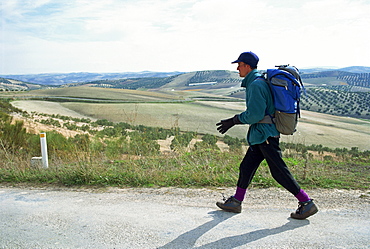 Backpacker walking on road, Andalucia, Spain, Europe