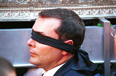 Malaga-Spain - Easter Week (Semana Santa) - A blindfolded member of a brotherhood helps to carry a float during a procession on Palm Sunday 