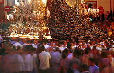 Malaga-Spain - Easter Week (Semana Santa) - Crowds mill around the giant cloak of the Virgen de la Trinidad as her float passes through the city streets 