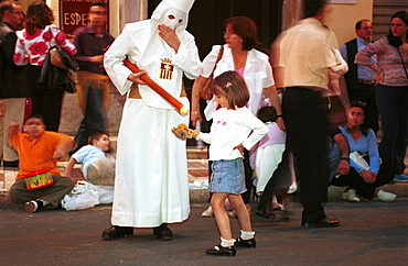 Malaga-Spain - Easter Week (Semana Santa) - A girl collects candle wax from a penitent during a procession 