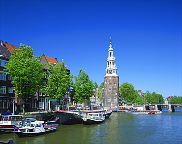 Boats on the Ovde Schans Canal with the Montelbaanstoren tower behind, in Amsterdam, Holland, Europe