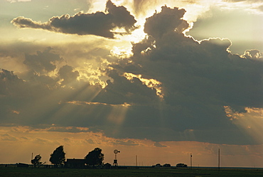 Rays of sun light landscape from behind dark towering clouds