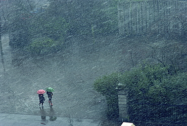 Two lone figures with umbrellas caught in rain storm, Dublin, Republic of Ireland, Europe