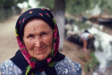 Portrait of an old woman in a black and pink head scarf in Romania, Europe