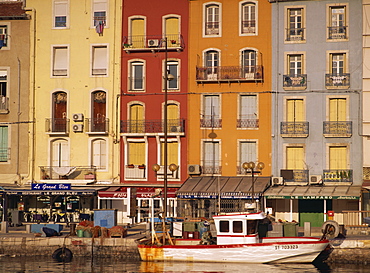 Boat, buildings with balconies and shops beneath on the waterfront, Sete, Languedoc, France, Europe