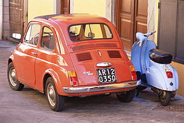 Fiat 500 car and old blue scooter parked together in back street, Tuscany, Italy, Europe