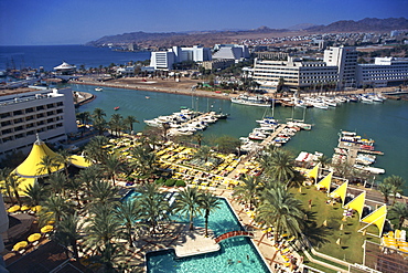 Aerial view over swimming pool, palm trees and the marina at Eilat, with modern buildings in the background, Israel, Middle East