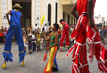 Group of people on stilts and in colourful costumes dancing and juggling in the street, Habana Vieja (Old Havana), Havana, Cuba, West Indies, Central America