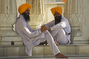 Two Sikhs priests with orange turbans, white dress and beards sitting under arcades, Golden Temple, Amritsar, Punjab state, India, Asia