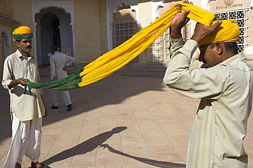 Guard winding his yellow and green turban, Moti Mahal courtyard, Meherangarh fort, Jodhpur, Rajasthan state, India, Asia