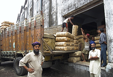 Truck drivers posing in front of tea sacks being unloaded at Carrit Moran & Company's tea warehouses at Kolkata port, Kolkata, West Bengal state, India, Asia