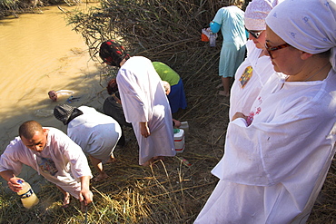 Russian pilgrims entering the water after Mass and filling water bottles with river water, Christian Orthodox ceremony at Epiphany, River Jordan, Qasr el Yahud, Israel, Middle East