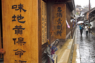 Village street on rainy day with local museum in foreground and women walking holding umbrellas, historical centre, Tomo No Ura fishing village, Hiroshima prefecture, Honshu, Japan, Asia