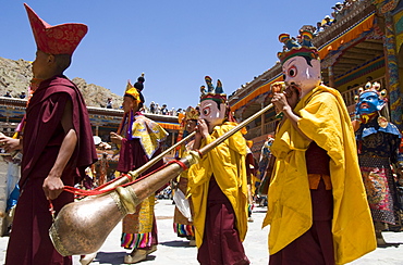 Procession in monastery courtyard with monk musicians wearing masks blowing traditional horns, Hemis Festival, Hemis, Ladakh, India, Asia