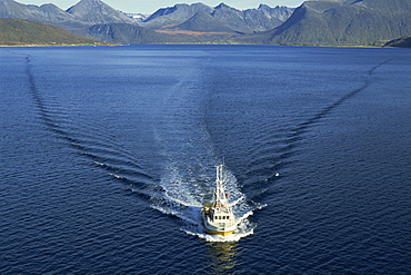 Aerial view over fishing boat and its wake, Arctic Norway, Scandinavia, Europe