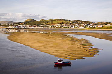 Red boat by exposed rippled sandbank on Conwy River estuary at low tide, with Deganwy beyond, Conwy, Wales, United Kingdom, Europe