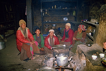 A group of Sherpa women indoors around a fire cooking, in the interior of a kitchen in a house in Solu Khumbu, Nepal, Asia