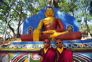 Thupten's twin monks, wearing sunglasses in front of a statue of the Buddha, outdoors, at the Swayambunath Stupa in Kathmandu, Nepal, Asia