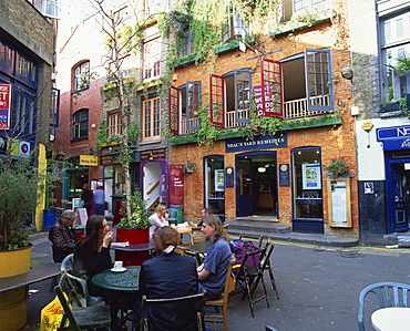 Small group of people sitting outdoors at tables of a cafe in Neal's Yard, Covent Garden, London, England, United Kingdom, Europe