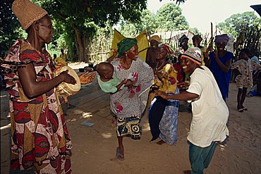 Small group of people, including woman with her baby, dancing outdoors, Gambia, West Africa, Africa