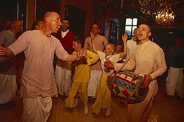 Portrait of a group of Hare Krishna devotees indoors dancing and playing a drum, England, United Kingdom, Europe