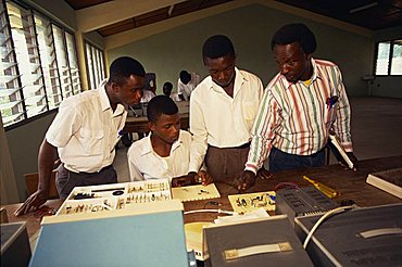 Teacher with three teenage students taking a science lesson in a school or college, Ghana, West Africa, Africa