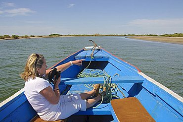 Tourist birdwatching from pirogue or fishing boat on the backwaters of the Sine Saloum delta, Senegal, West Africa, Africa