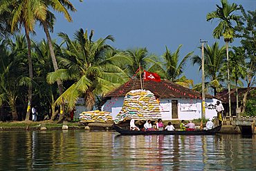 Small boat passing Communist flag, Backwaters, Kerala state, India, Asia