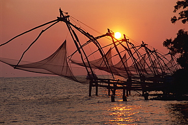 A line of Chinese fishing nets on the coast at sunset, Fort Cochin, Kerala, India, Asia