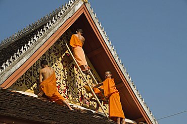 Monks on roof painting the temple decorations, Wat Mai, Luang Prabang, Laos, Indochina, Southeast Asia, Asia