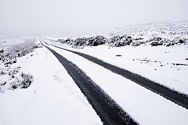 Car tyre tracks on a snowy road on the Mynydd Epynt moorland, Powys, Wales, United Kingdom, Europe