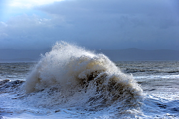 Huge waves crash against a stone jetty at Criccieth, Gwynedd, Wales, United Kingdom, Europe