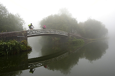 A cyclist on a bridge on Birmingham Canal Navigations (BCN), Birmingham, West Midlands, England, United Kingdom, Europe