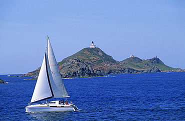 Sailing boat with the Semaphore Lighthouse behind, Iles Sanguinaires, island of Corsica, France, Mediterranean, Europe