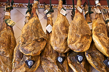 Spanish hams hanging in a restaurant bodega, Seville, Andalusia, Spain, Europe