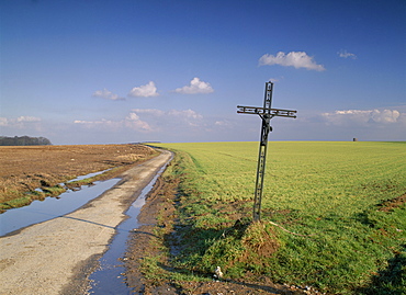 Christian calvary beside muddy track and fields in landscape near Agincourt, Nord Pas de Calais, France, Europe