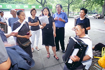 Group of people singing to accordian music, Shanghai, China, Asia