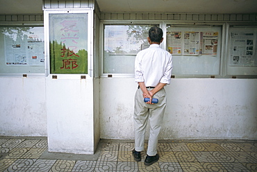 Reading newspaper on public noticeboard, Shanghai, China, Asia