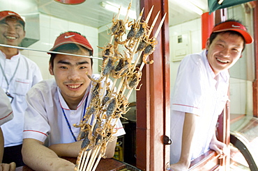 Eating a snack of skewers of scorpion at a hutong near Wang Fu Jing road, where grasshopper, sea horse, snakes, larva and starfish also served, Beijing, China, Asia