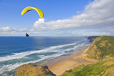 Paraglider with yellow wing above the south west coast of Portugal, Costa Vincentina, Praia do Castelejo and Cordama beaches near Vila do Bispo, Algarve, Portugal, Europe 