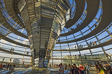 Visitors walk up a spiralling ramp around the cone shaped funnel in the dome cupola, which has 360 glass mirrors reflecting light into the Plenary chamber of the Reichstag building, designed by Sir Norman Foster, Berlin, Germany, Europe