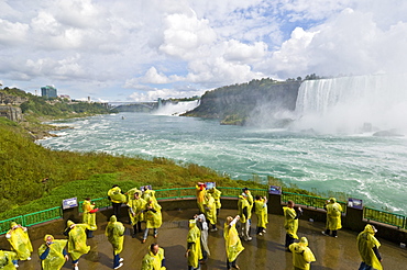 Many tourists in yellow raincoats in the spray of the Horseshoe Falls waterfall whilst on the Journey under the Falls tour, Niagara Falls, Ontario, Canada, North America