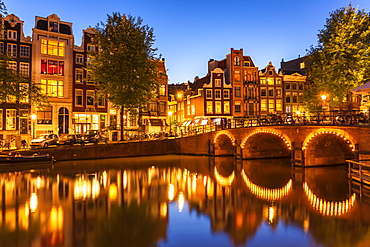 Illuminated canal bridge with reflections at night over the Singel Torensluis canal, Amsterdam, North Holland, Netherlands, Europe