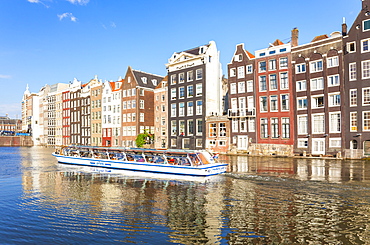 Row of typical Dutch houses on Damrak Canal with canal tour boat, Amsterdam, North Holland, Netherlands, Europe