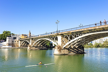 Rower going under the Triana bridge over the Guadalquivir River, Triana district, Seville, Spain, Andalusia, Spain, Europe